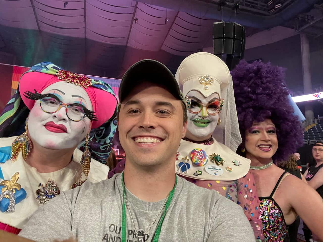 Out, Proud, and Healthy employee poses with drag queens.